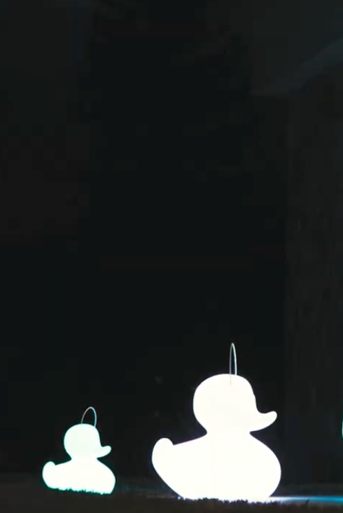 Goodnight Light Duck Duck lamp in three sizes on the terrace in front of a villa, lights on glowing